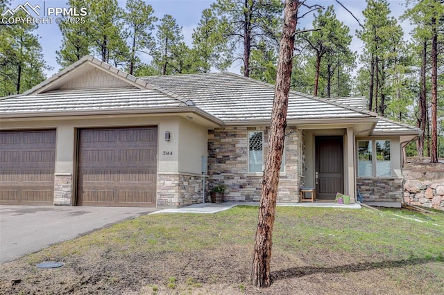 view of front of home with stone siding, a tile roof, driveway, and stucco siding