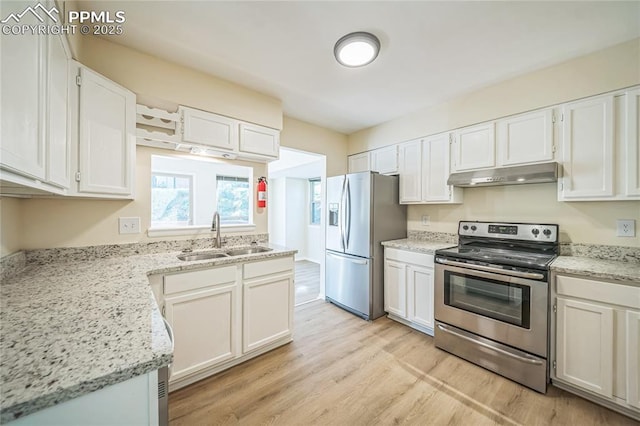 kitchen with appliances with stainless steel finishes, a sink, under cabinet range hood, light wood-type flooring, and white cabinets