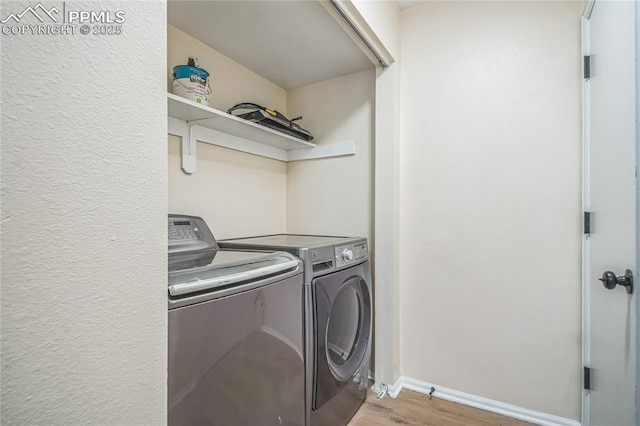 laundry area featuring washing machine and clothes dryer, light wood-style flooring, and baseboards