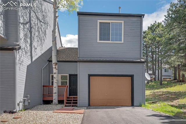 rear view of house with an attached garage and a wooden deck