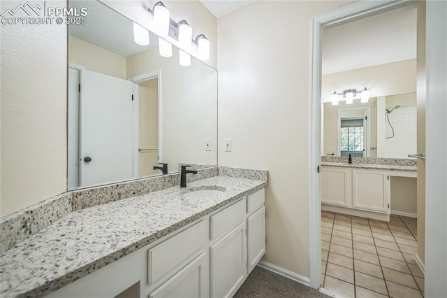 bathroom with baseboards, tile patterned floors, and two vanities
