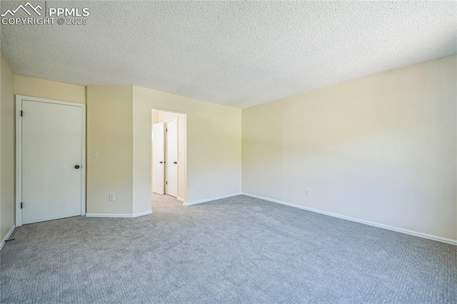 carpeted empty room featuring baseboards and a textured ceiling