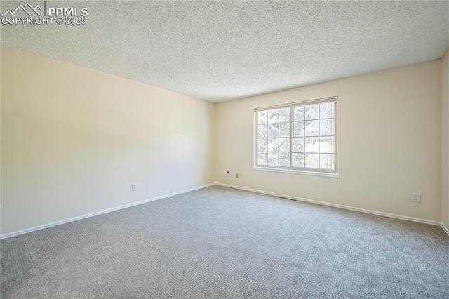 carpeted spare room featuring a textured ceiling and baseboards