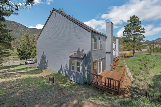 view of home's exterior featuring a chimney and a deck with mountain view