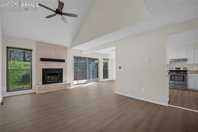 unfurnished living room with ceiling fan, dark wood-style floors, healthy amount of natural light, a fireplace, and high vaulted ceiling