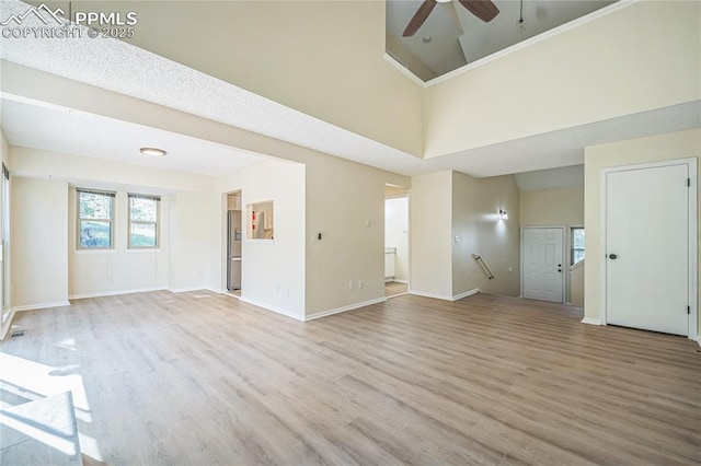 unfurnished living room featuring ceiling fan, wood finished floors, and baseboards