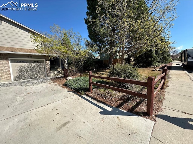 view of yard featuring fence and concrete driveway