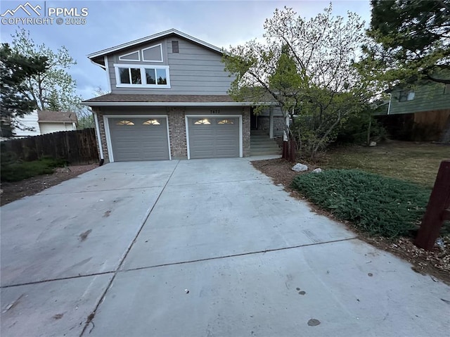 view of front of house with concrete driveway, an attached garage, fence, and brick siding