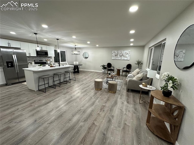 living area with recessed lighting, light wood-style floors, and baseboards
