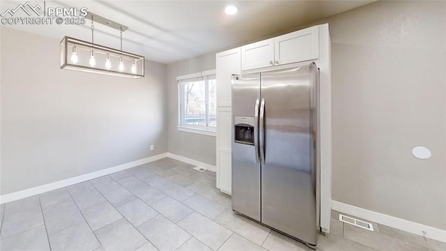 1636 Shenandoah Dr, Colorado Springs, CO 80910 - kitchen with stainless steel fridge, white cabinets, baseboards, light tile patterned floors, and hanging light fixtures