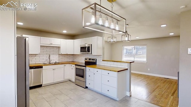 1636 Shenandoah Dr, Colorado Springs, CO 80910 - kitchen featuring appliances with stainless steel finishes, a sink, wood counters, backsplash, and recessed lighting