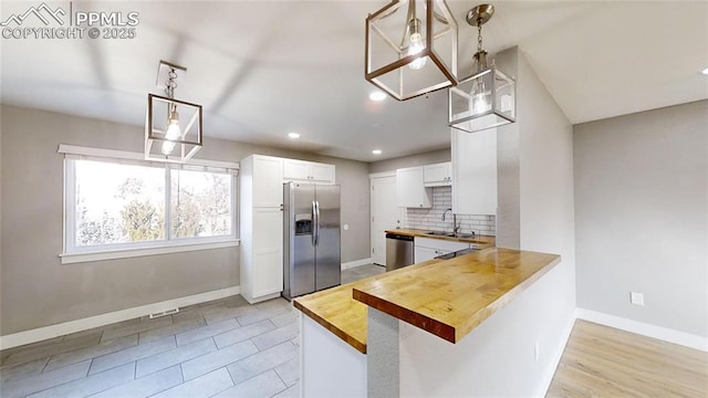 1636 Shenandoah Dr, Colorado Springs, CO 80910 - kitchen featuring appliances with stainless steel finishes, wooden counters, a sink, white cabinetry, and decorative backsplash