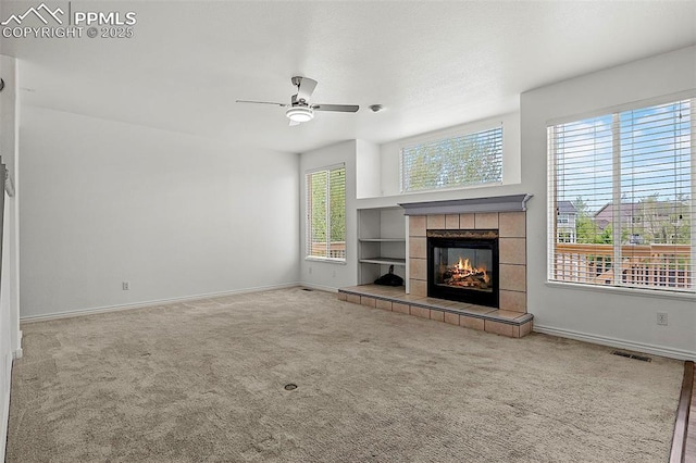unfurnished living room featuring a ceiling fan, baseboards, carpet floors, and a tile fireplace