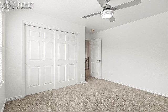 unfurnished bedroom featuring carpet floors, a closet, baseboards, and a ceiling fan