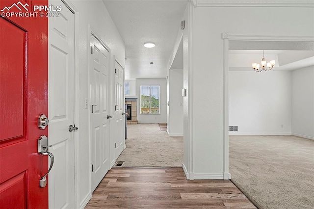 corridor with carpet flooring, a chandelier, baseboards, and wood finished floors