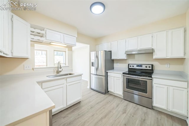 kitchen with stainless steel appliances, a sink, under cabinet range hood, and white cabinetry