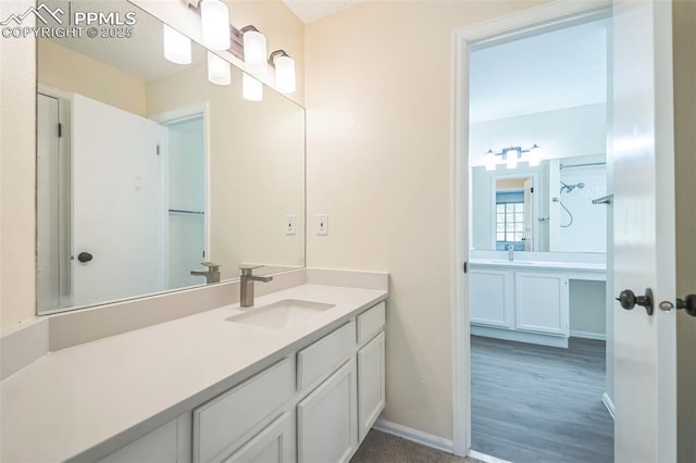 full bath with vanity, baseboards, and wood finished floors