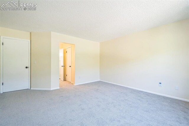 unfurnished bedroom featuring light carpet, a textured ceiling, and baseboards