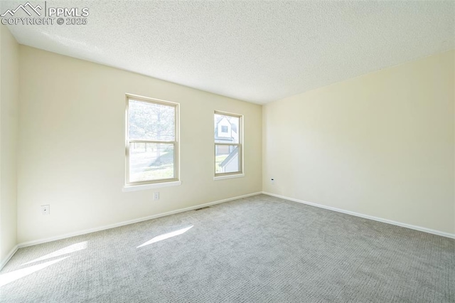 carpeted empty room with a textured ceiling and baseboards