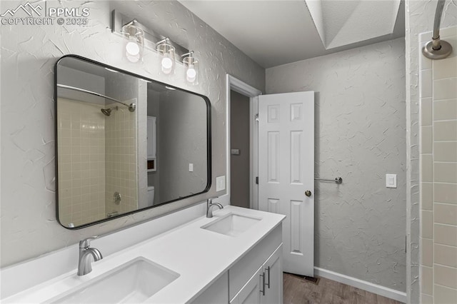bathroom featuring wood finished floors, a shower, and double vanity