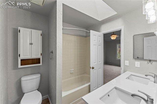 bathroom featuring toilet,  shower combination, a textured wall, and double vanity