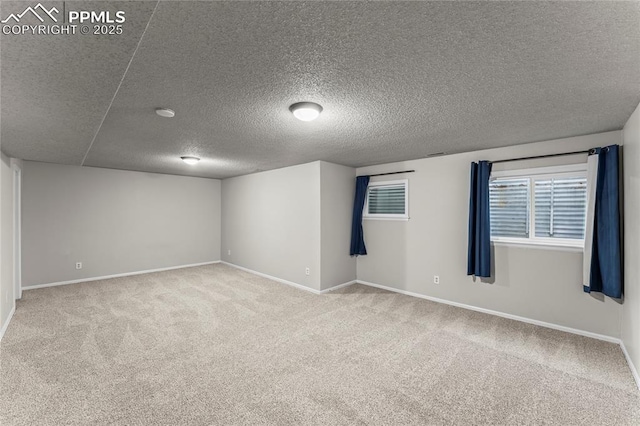 carpeted empty room with a textured ceiling and baseboards