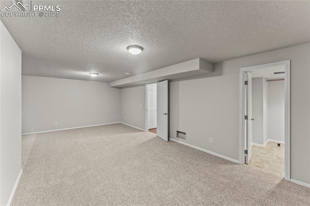 finished basement with carpet floors, a textured ceiling, and baseboards
