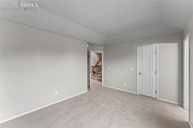 spare room with carpet floors, baseboards, and a textured ceiling