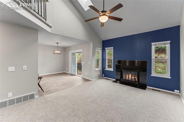 unfurnished living room with carpet floors, plenty of natural light, ceiling fan, baseboards, and high vaulted ceiling