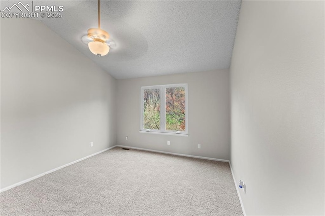 carpeted spare room with a textured ceiling and baseboards