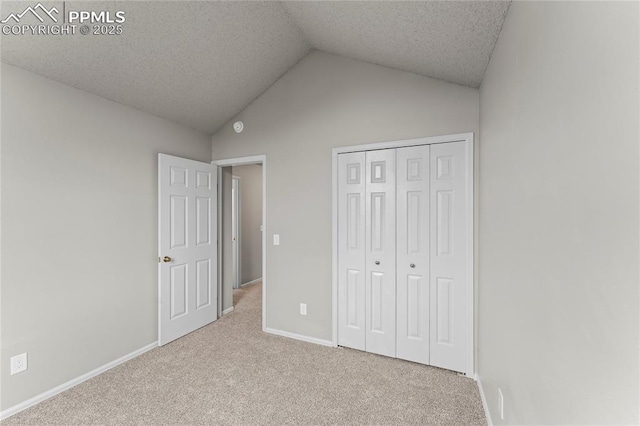unfurnished bedroom with carpet floors, lofted ceiling, baseboards, a closet, and a textured ceiling