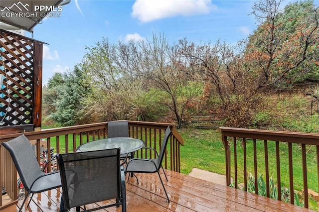 deck featuring outdoor dining space and a lawn