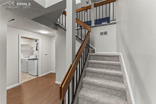 stairway featuring independent washer and dryer, wood finished floors, baseboards, and a textured ceiling