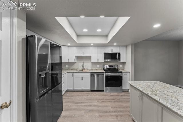 kitchen with appliances with stainless steel finishes, a sink, light wood-style floors, recessed lighting, and white cabinets