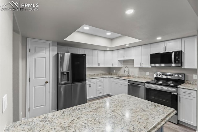 kitchen with stainless steel appliances, a sink, recessed lighting, white cabinets, and light stone counters