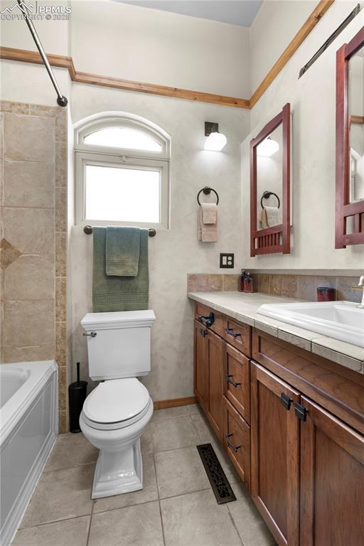 bathroom featuring vanity, toilet, tile patterned flooring, and bathtub / shower combination