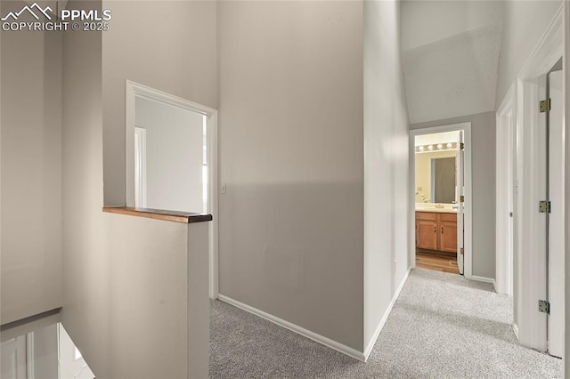corridor featuring carpet floors, a high ceiling, and baseboards