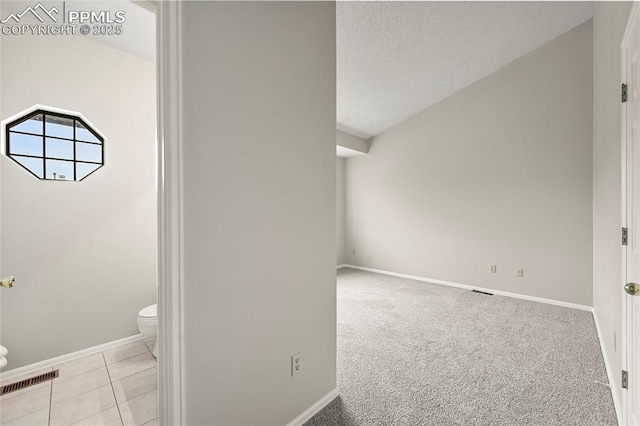 bathroom with toilet, baseboards, a textured ceiling, and tile patterned floors