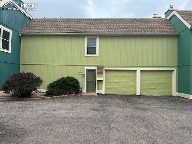 1769 Woodmoor Dr, Monument, CO 80132 - view of front facade featuring roof with shingles, a garage, a chimney, and driveway