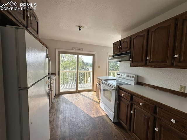 1769 Woodmoor Dr, Monument, CO 80132 - kitchen with white appliances, under cabinet range hood, dark wood-type flooring, a textured ceiling, and dark brown cabinetry