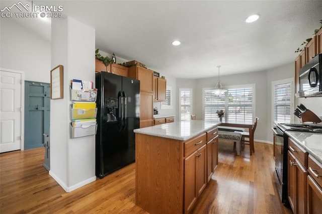 kitchen featuring black appliances, light wood-style flooring, baseboards, brown cabinets, and a kitchen island