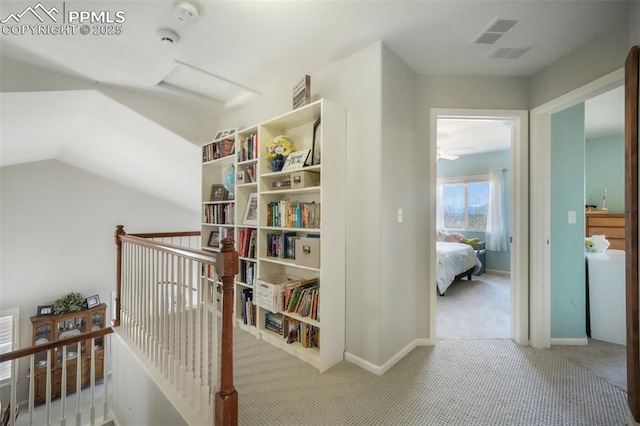 corridor with carpet floors, attic access, an upstairs landing, lofted ceiling, and baseboards