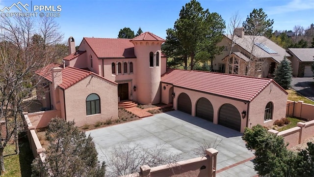 3285 El Pomar Rd, Colorado Springs, CO 80906 - mediterranean / spanish house featuring concrete driveway, an attached garage, a tiled roof, fence, and stucco siding