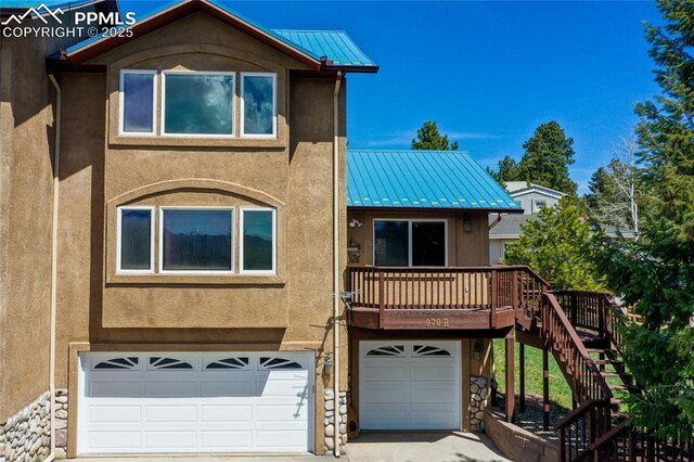 view of front facade with a garage, metal roof, stairs, stucco siding, and a standing seam roof