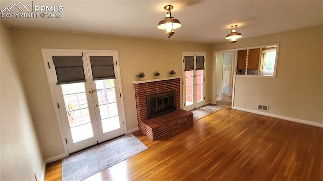 unfurnished living room with french doors, wood finished floors, baseboards, and plenty of natural light