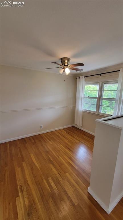 unfurnished room with wood finished floors, baseboards, and a ceiling fan