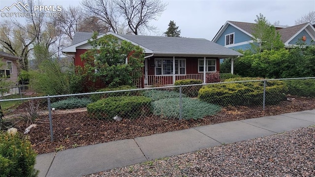 bungalow featuring covered porch, a fenced front yard, and board and batten siding