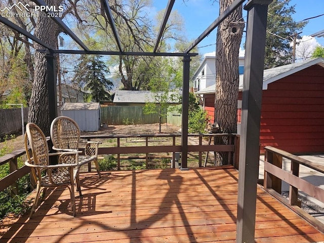 wooden deck with a fenced backyard, a storage shed, and an outdoor structure