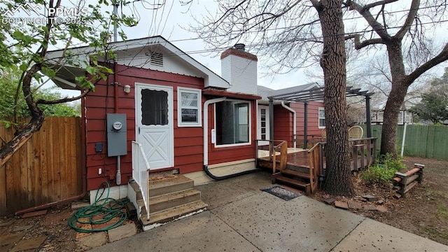 rear view of property with fence, a chimney, a deck, and a pergola