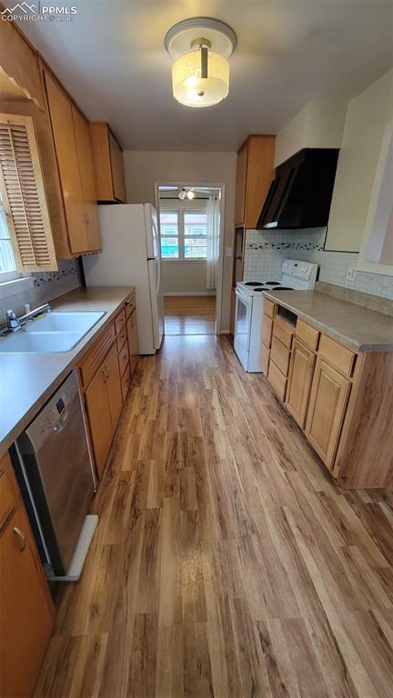 kitchen with white appliances, a sink, decorative backsplash, light wood-type flooring, and ceiling fan